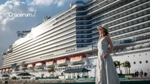 mujer parada de lado y al fondo se ve un barco de cruceros atracado en puerto como prepararse para un crucero vuelta al mundo crucerum